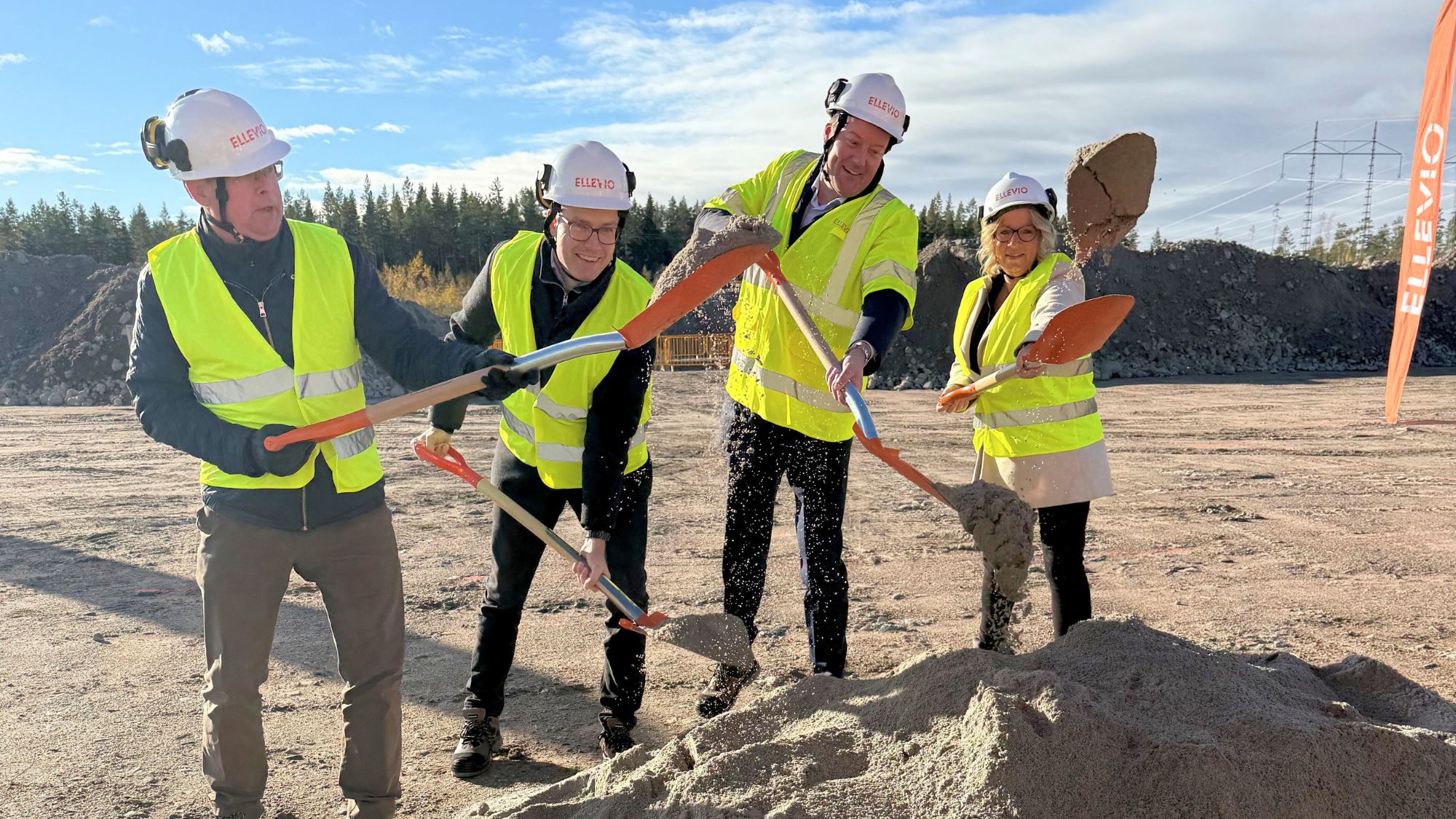 Personer i reflexvästar deltar i ett symboliskt första spadtag