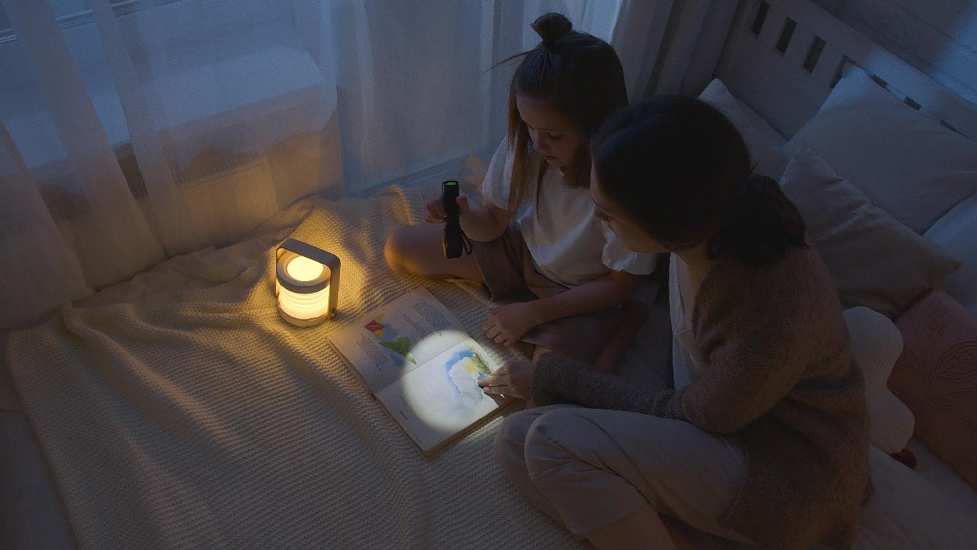 Vuxen och barn sitter i mörkret och gör läxor tillsammans i skenet av ficklampa