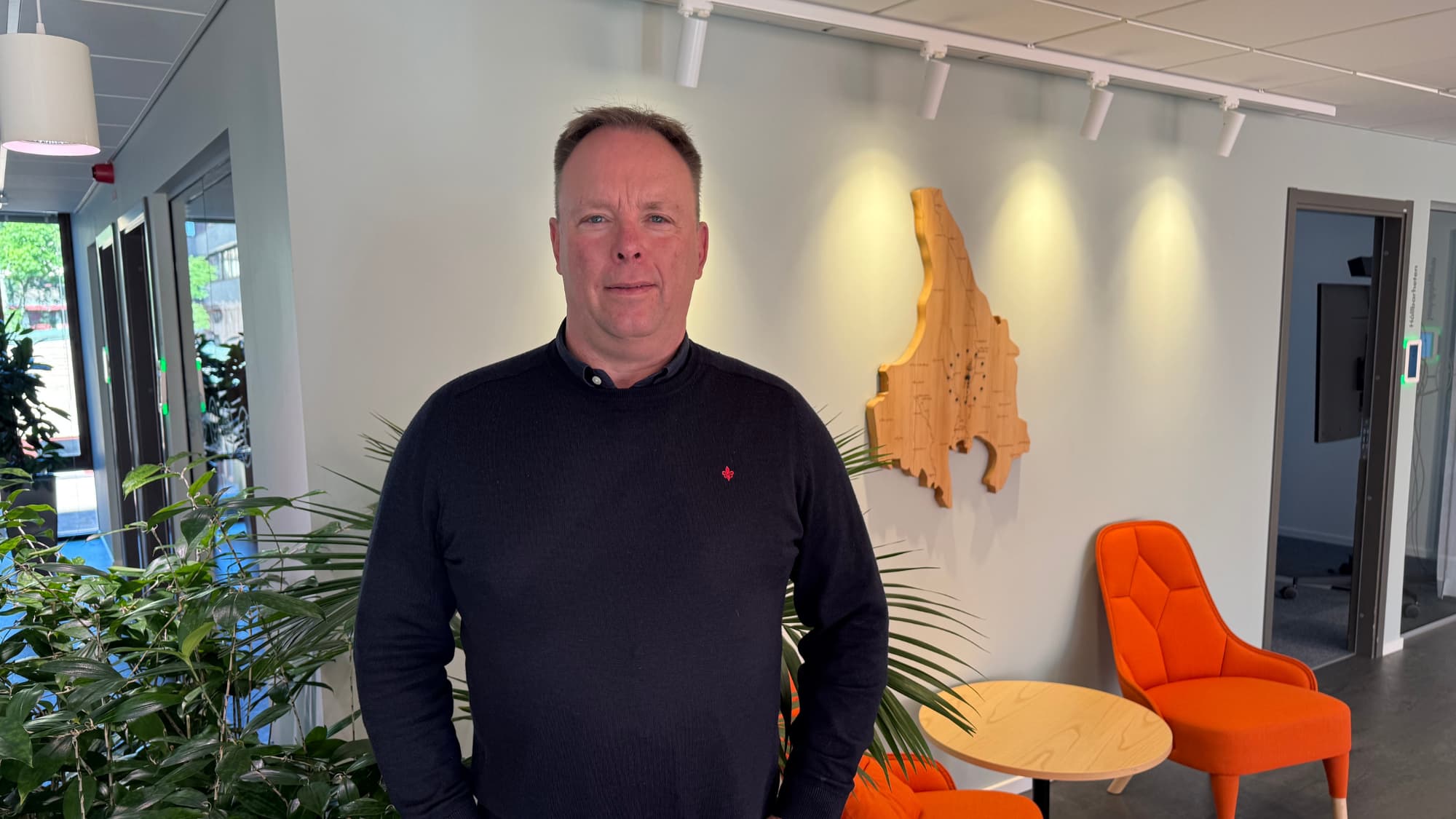 Christian Skoglund står framför några orangea fotöljer 