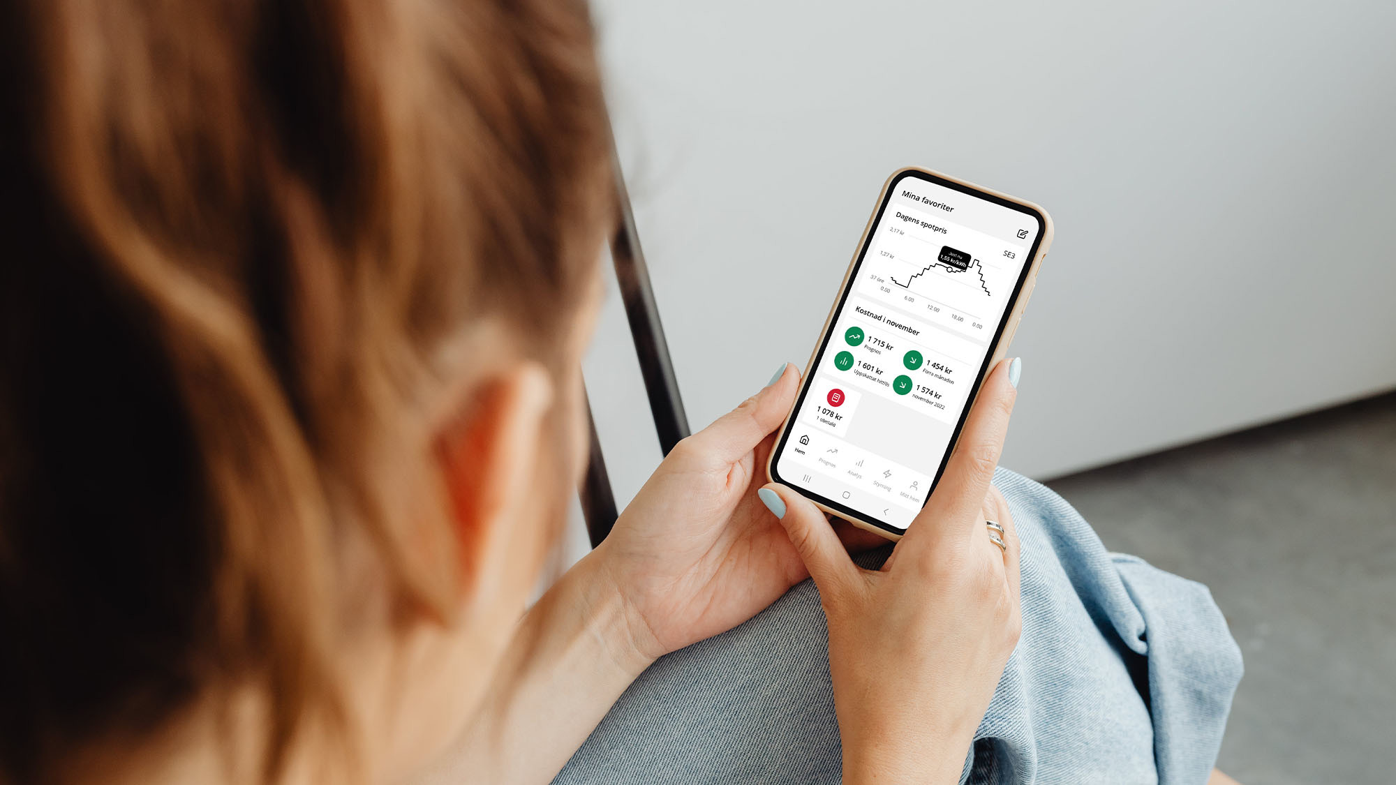 Kvinna i soffa med Ellevios app i mobilen