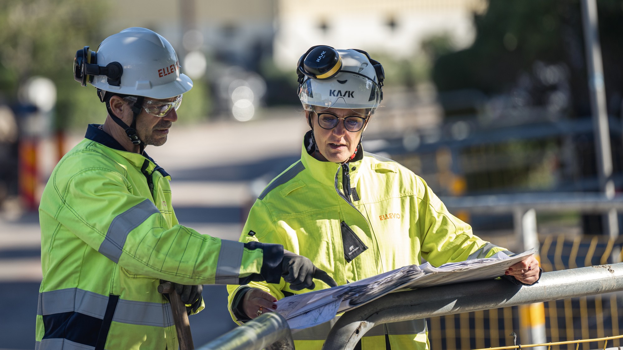 Tv&aring; Ellevio-medarbetare st&aring;r och diskuterar bredvid varandra vid ett projekt. 