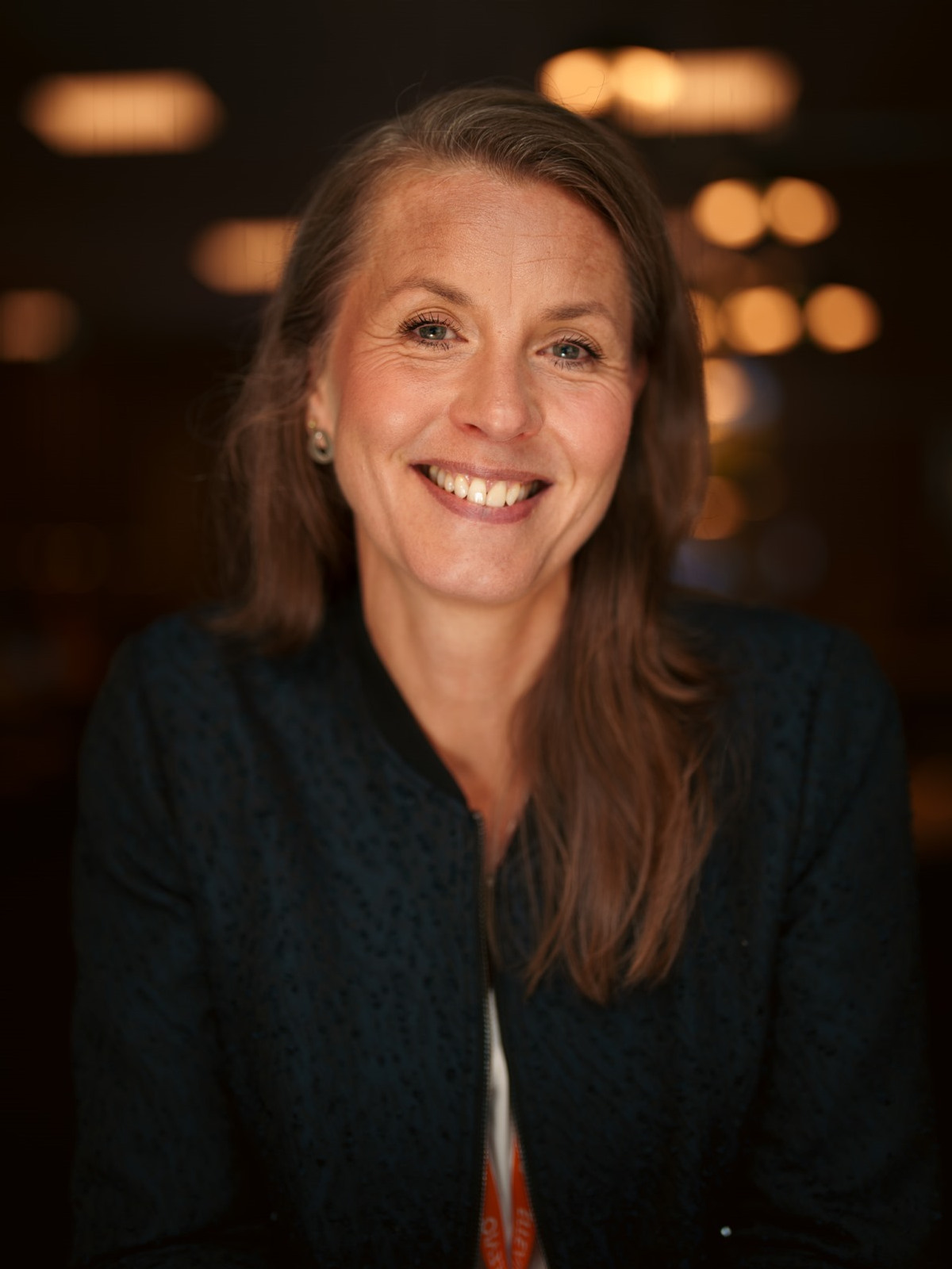 En kvinna med l&aring;ngt h&aring;r som ler mot kameran.