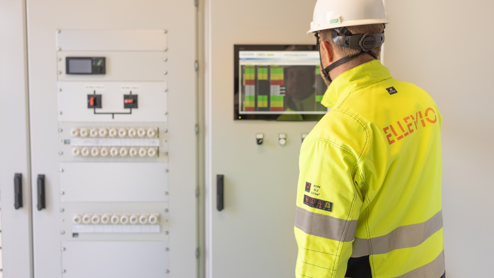 En man i skyddshjälm står framför en maskin.