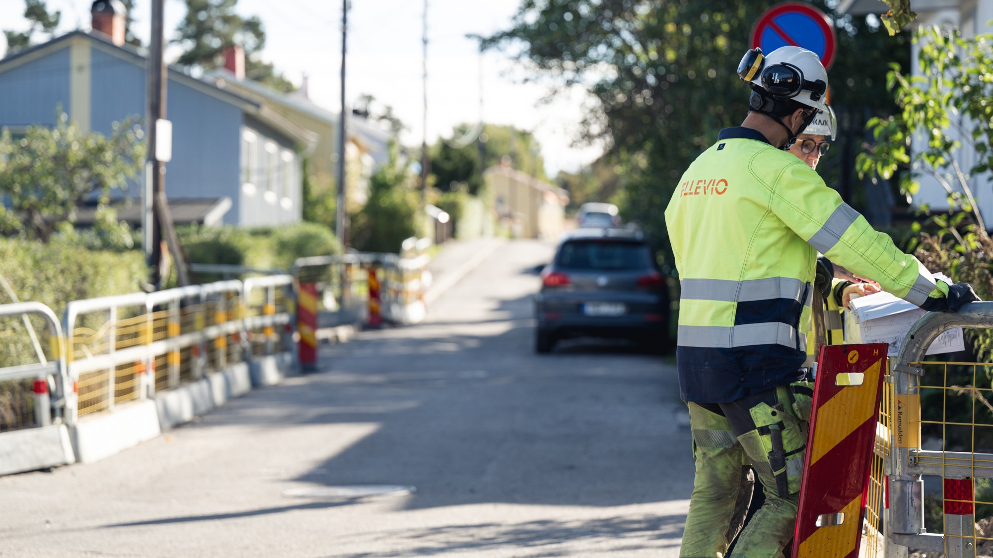 En man i skyddsväst står bredvid ett staket.