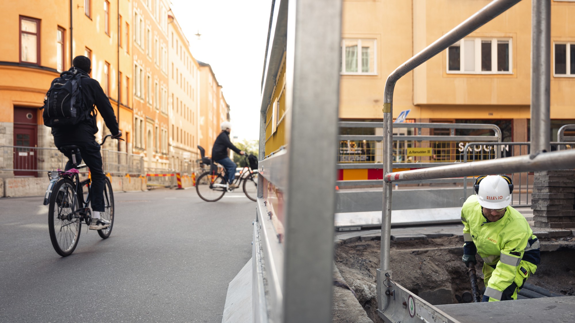 En man cyklar längs en gata bredvid en annan man på cykel.