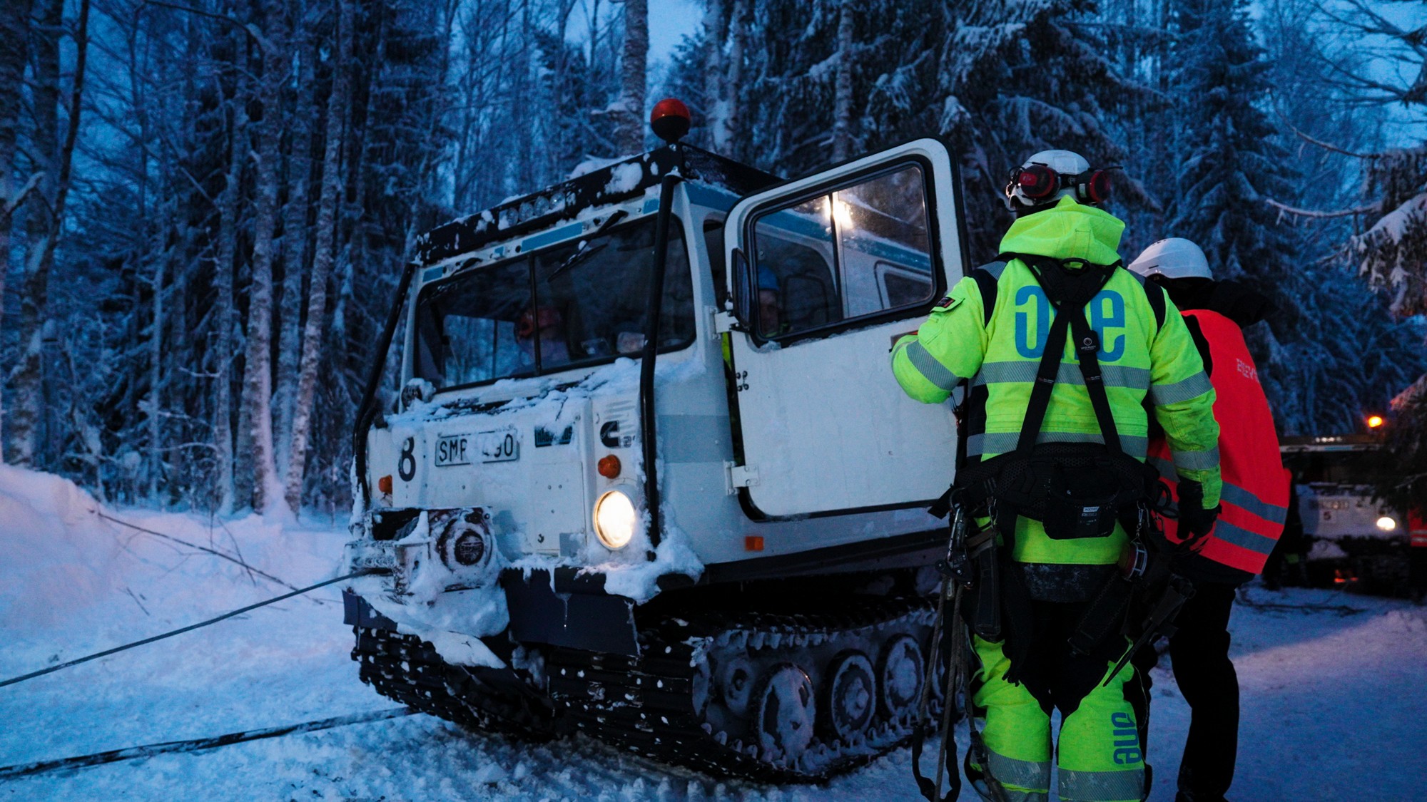Två montörer står framför en bandvagn.