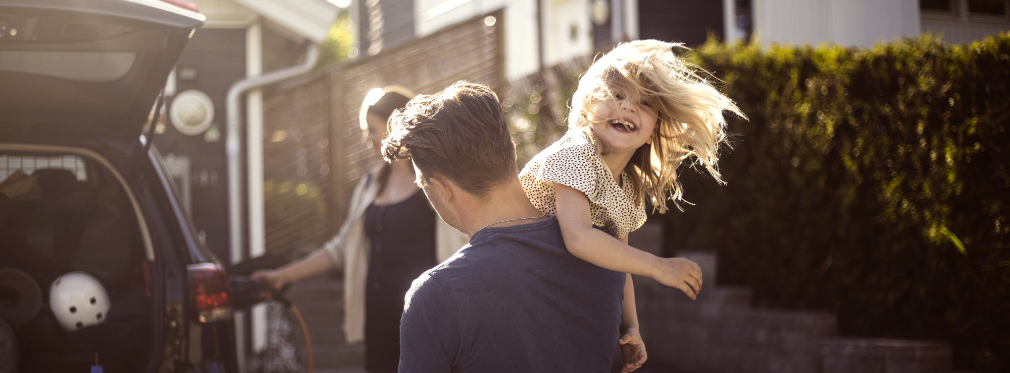 En man bär en liten flicka på väg till bilen