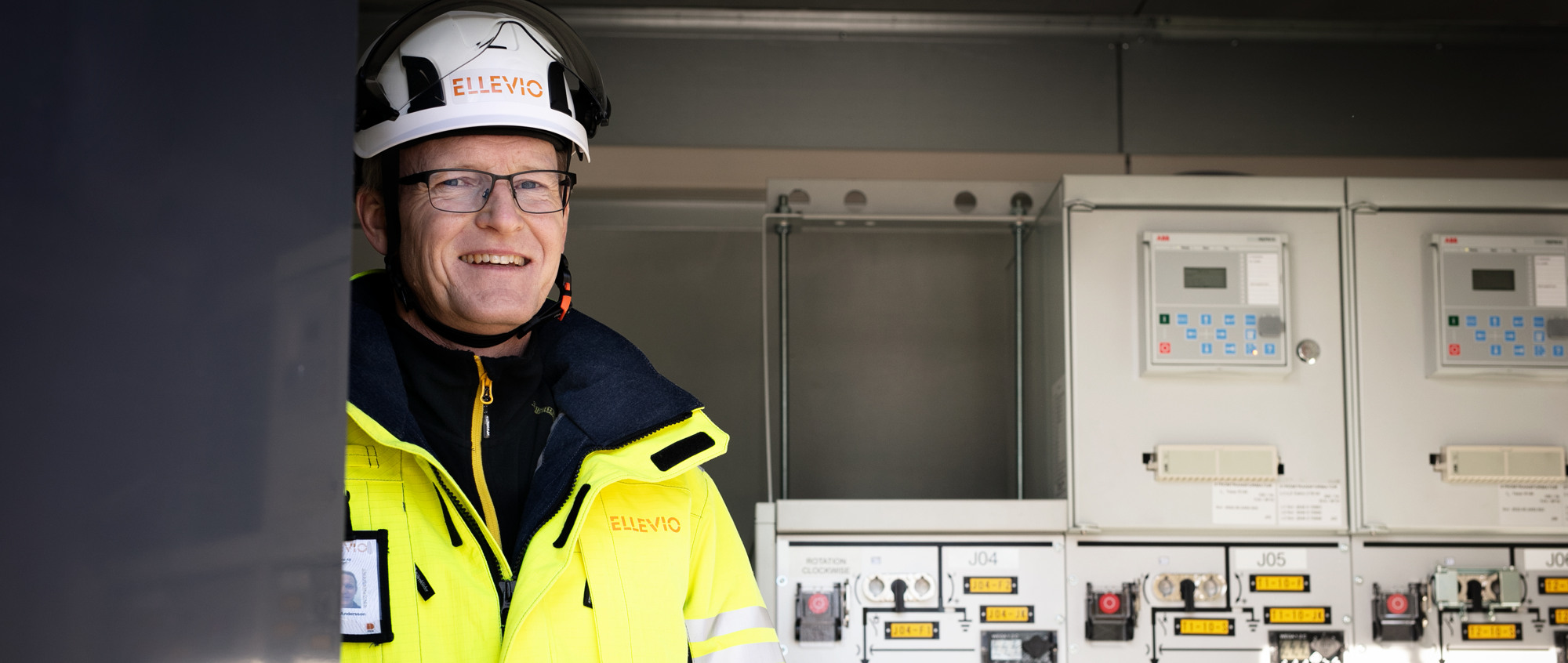 En man i skyddshjälm står framför ett kontrollrum.