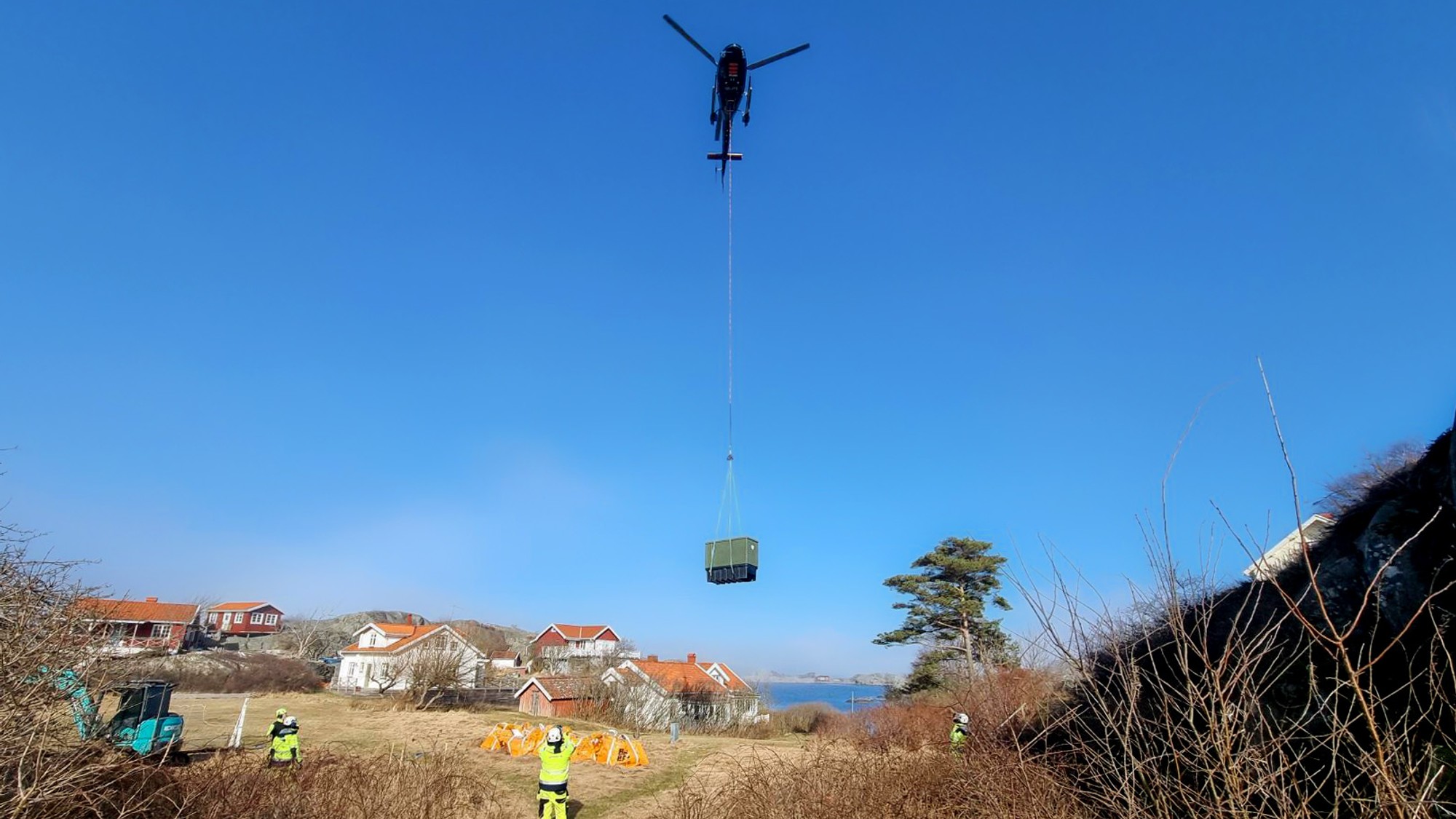 En helikopter som flyger över ett fält med en person i förgrunden.