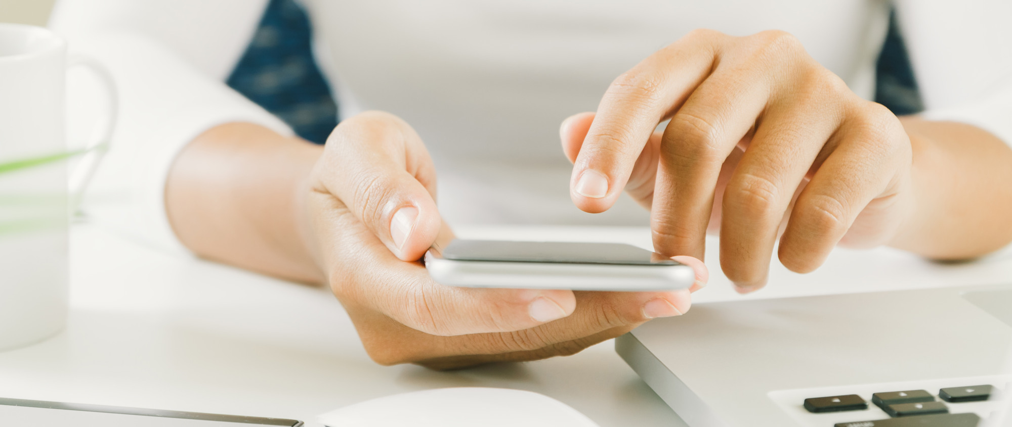 En kvinna som sitter vid ett skrivbord och håller en mobiltelefon.