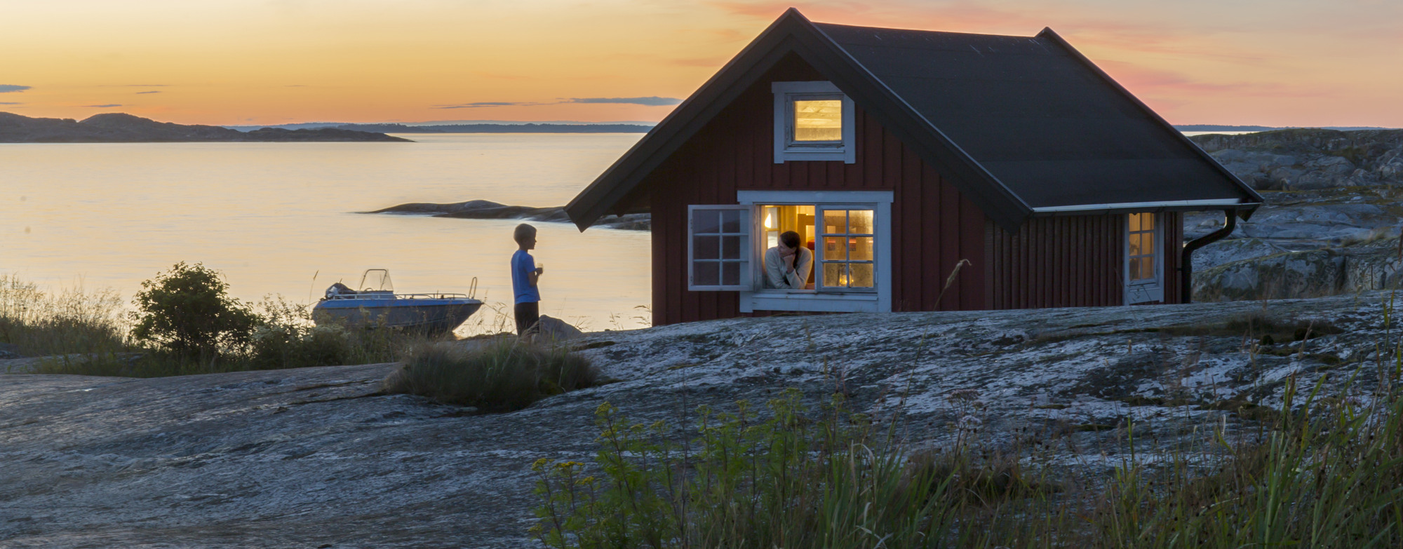 En röd stuga intill havet.
