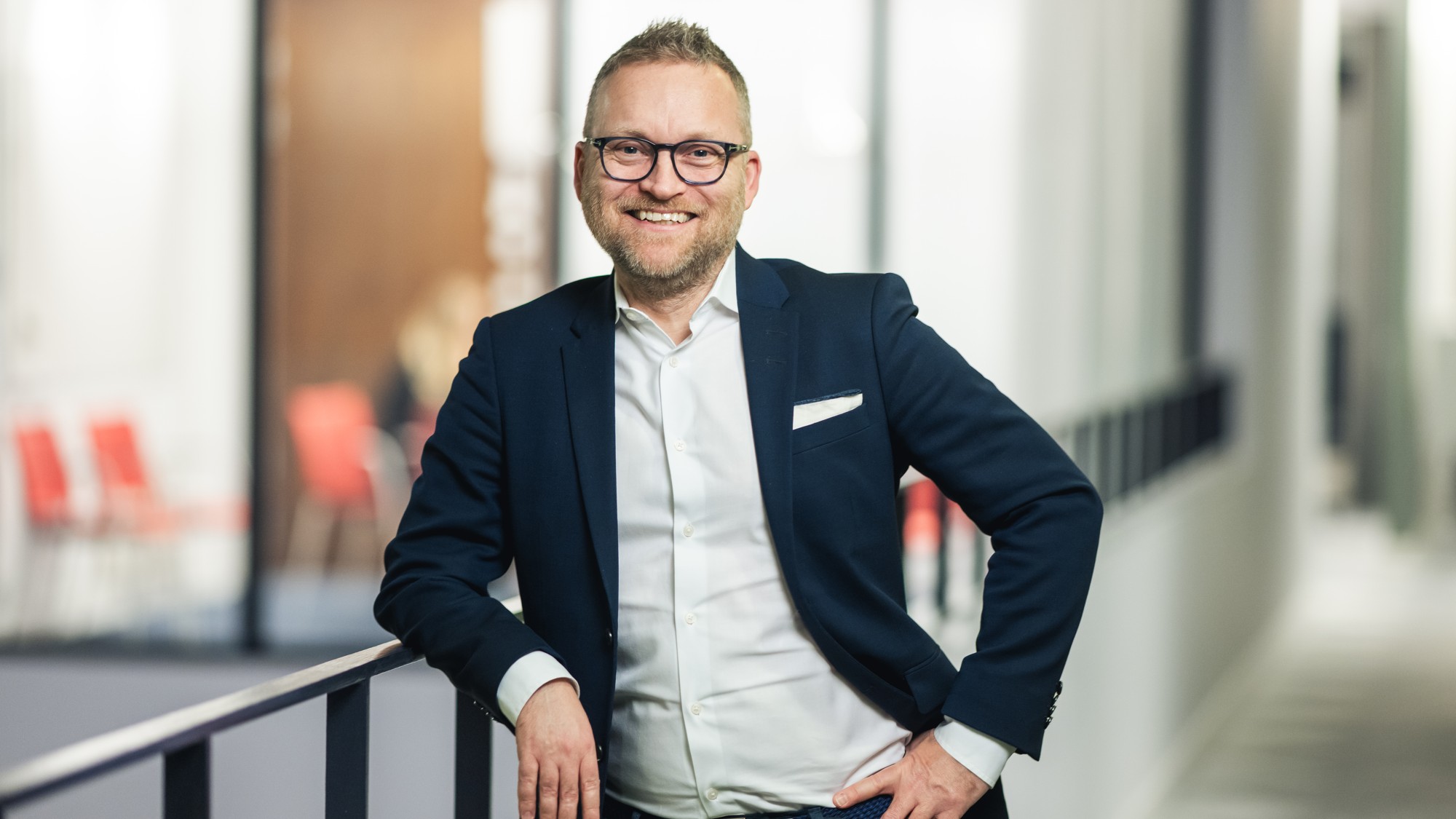 En man i kostym och slips st&aring;r p&aring; en balkong.