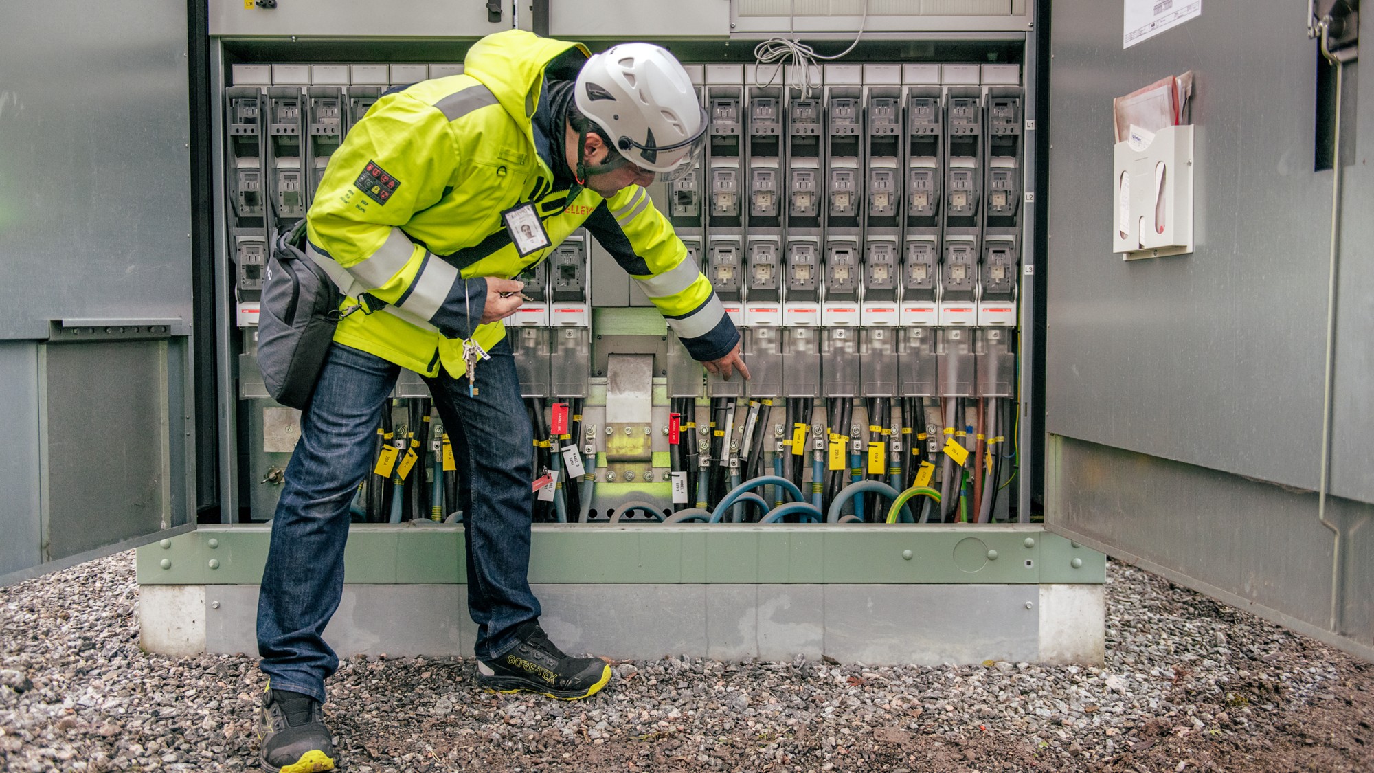 En man i skyddskläder står intill en öppen nätstation.
