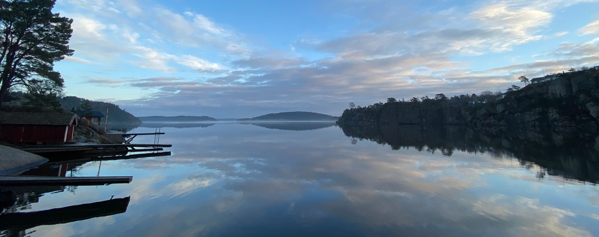 A body of water surrounded by trees and clouds.