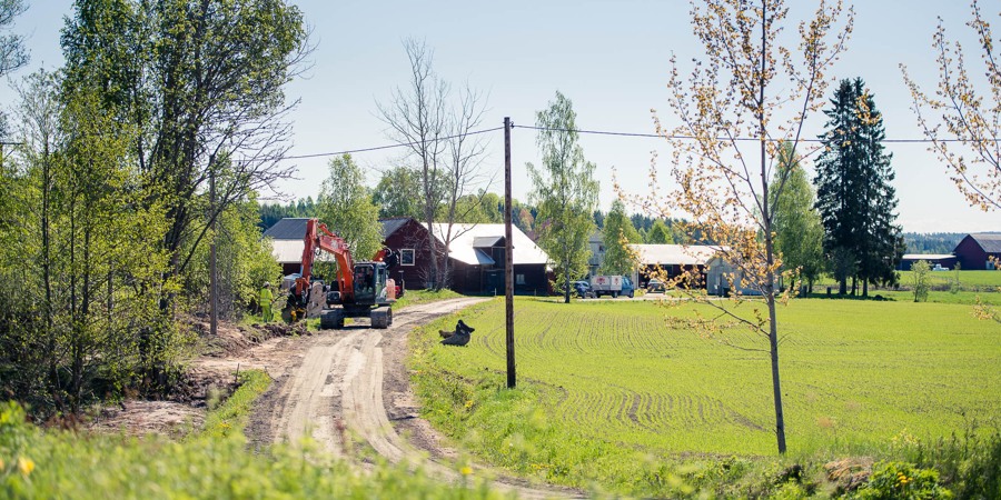 En lastbil kör på en grusväg bredvid ett grönskande fält.