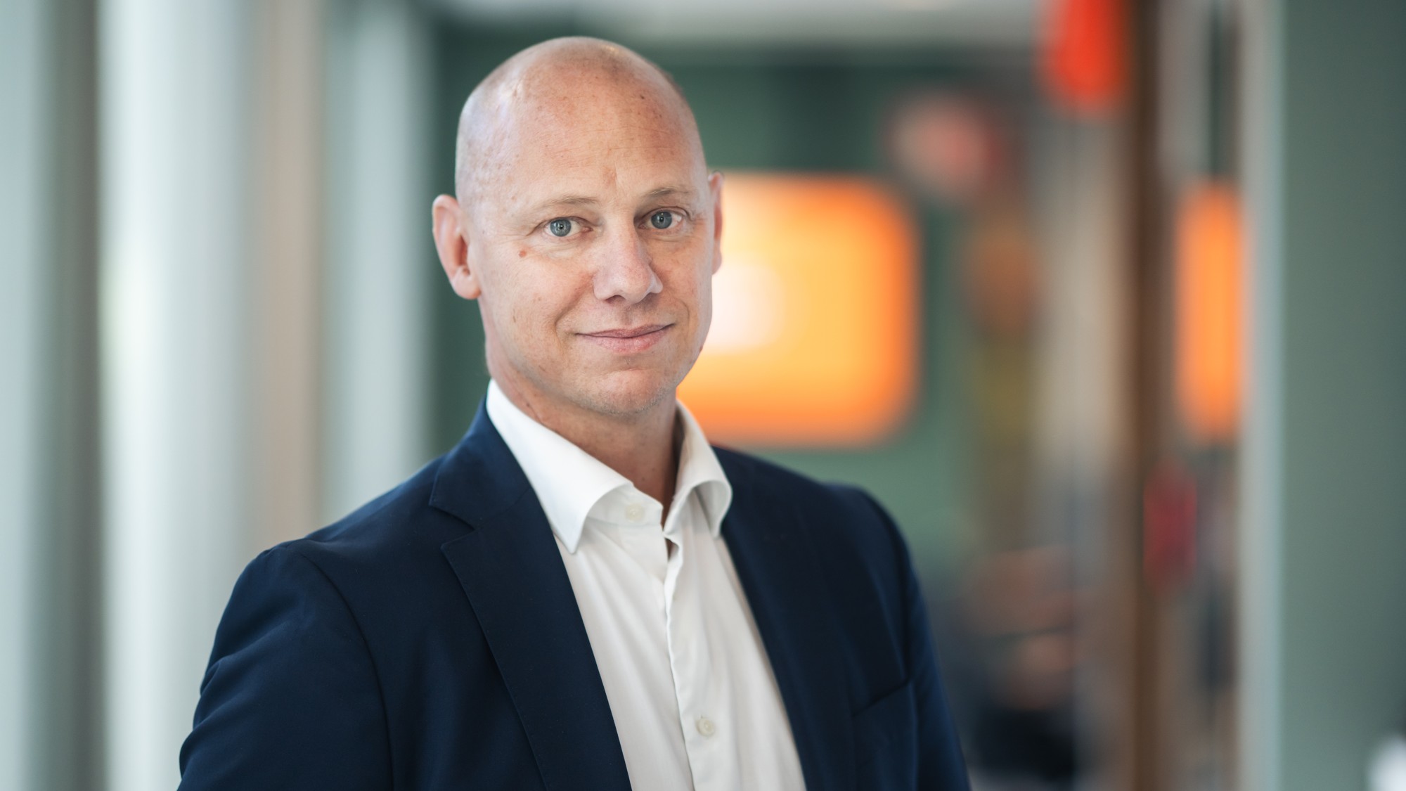 En man i kostym st&aring;r i en korridor.