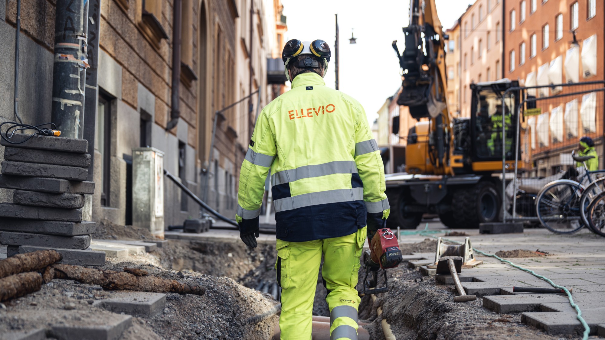 En man i gul skyddsdräkt går längs en gata.