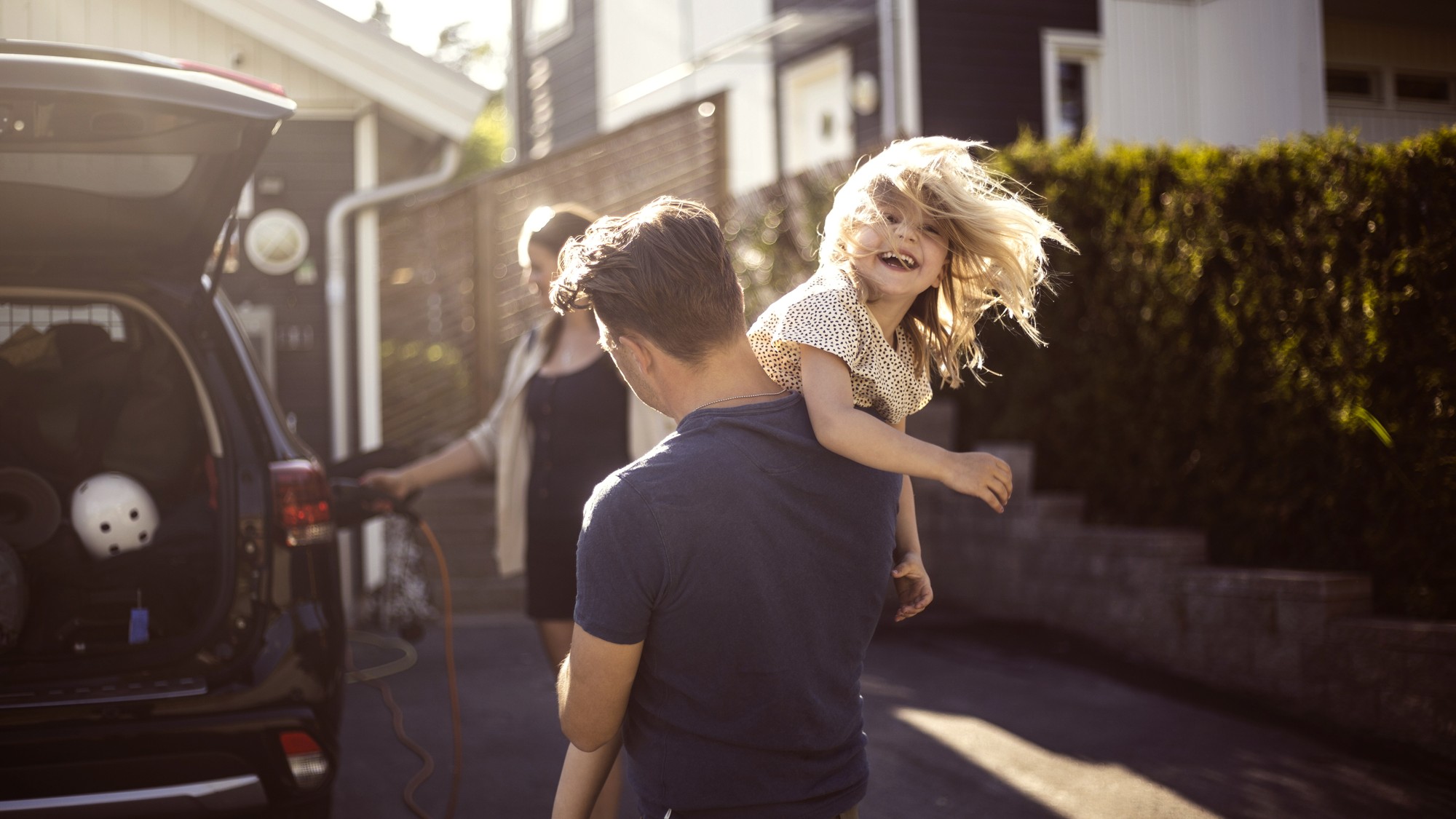 Familj st&aring;r vid elbil som laddar
